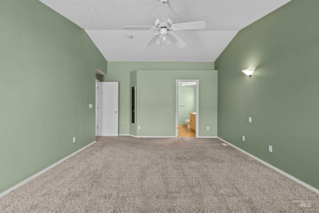 unfurnished bedroom with ceiling fan, ensuite bathroom, a textured ceiling, light carpet, and vaulted ceiling