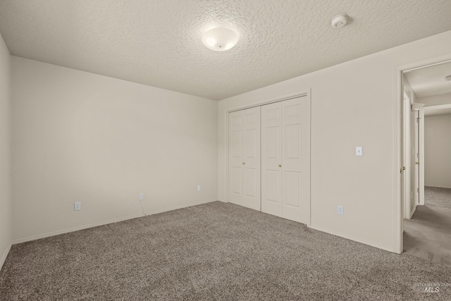 unfurnished bedroom featuring carpet floors, a closet, and a textured ceiling