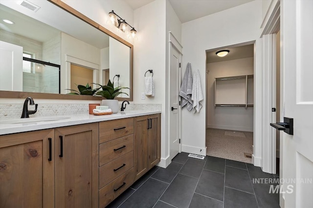 bathroom with tile patterned floors, walk in shower, and vanity