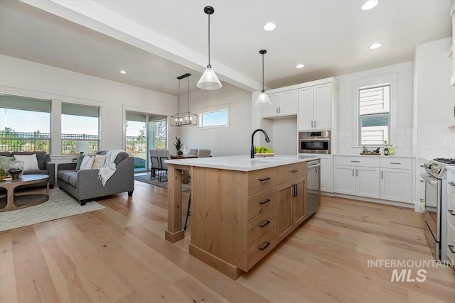 kitchen featuring pendant lighting, white cabinets, a center island with sink, and stainless steel appliances