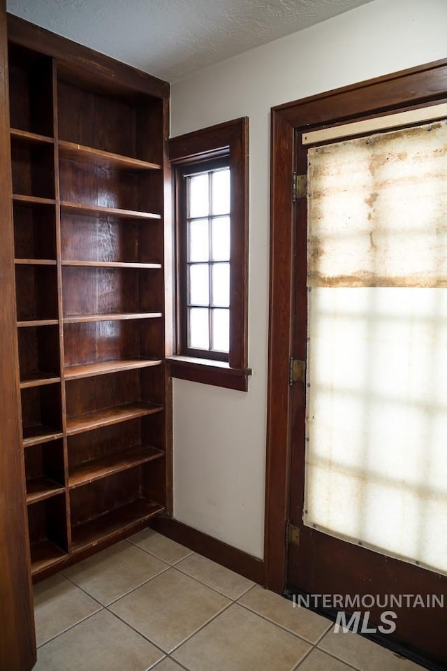 doorway with light tile patterned floors and a textured ceiling