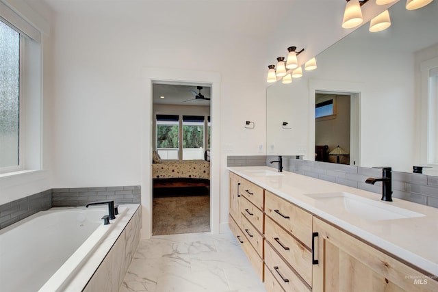 bathroom with tiled tub, vanity, and plenty of natural light