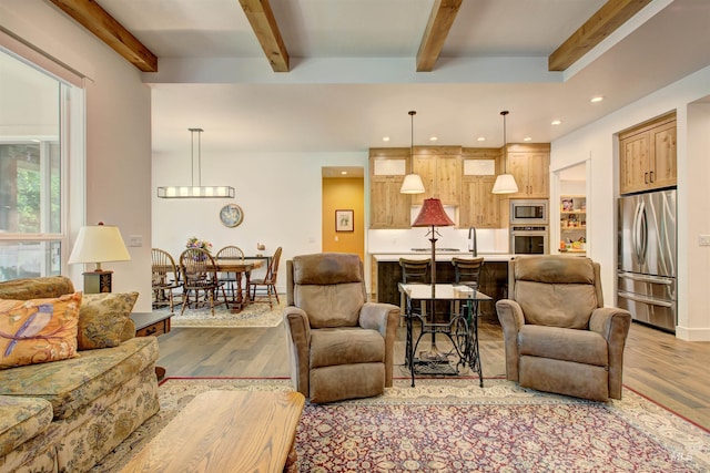 living room featuring sink, beam ceiling, and light hardwood / wood-style floors