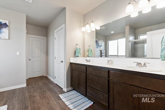 22924 Fargo Rd, Parma, ID 83660 - bathroom with baseboards, a sink, a stall shower, double vanity, and wood finished floors