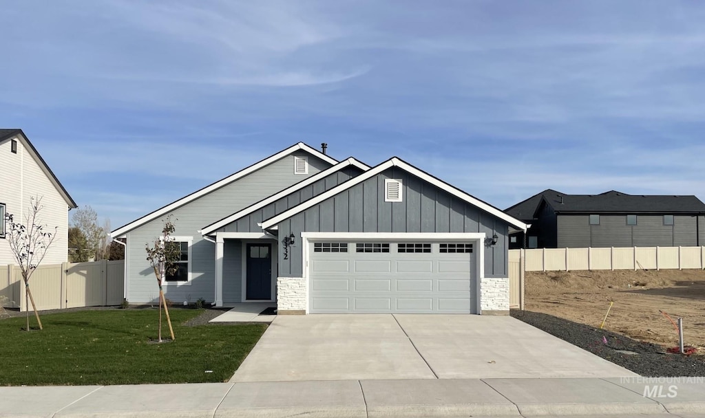 323 W Omphale St, Kuna, ID 83634 - view of front facade featuring board and batten siding, an attached garage, concrete driveway, and stone siding