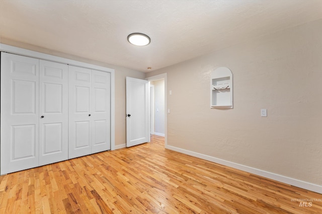 unfurnished bedroom featuring a closet, baseboards, and light wood finished floors