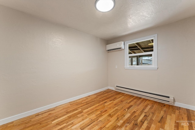 unfurnished room featuring a wall unit AC, baseboards, light wood finished floors, a textured ceiling, and a baseboard heating unit