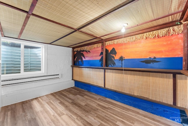 empty room featuring a baseboard heating unit and wood finished floors