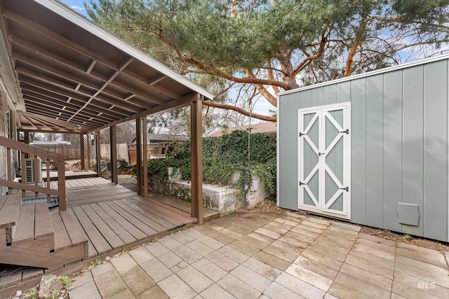 deck with an outbuilding, a storage unit, a fenced backyard, and a patio area