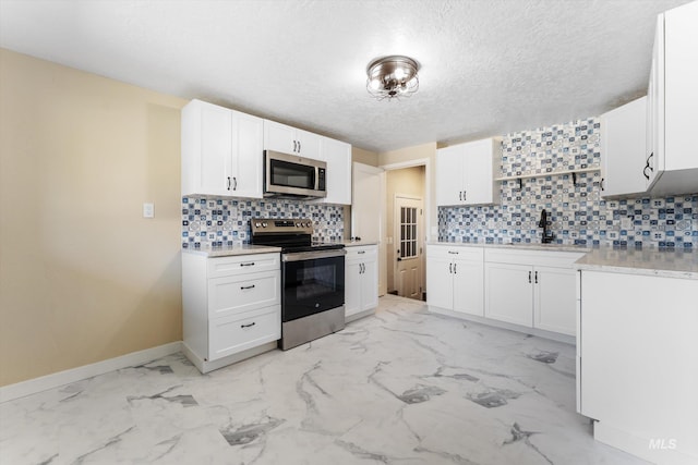 kitchen with marble finish floor, appliances with stainless steel finishes, white cabinetry, and a sink