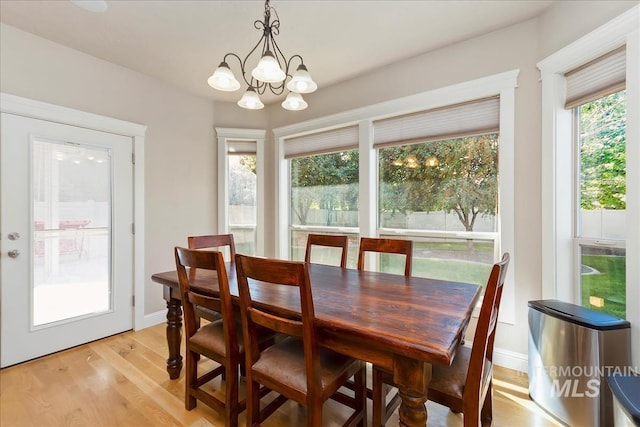 dining room with a chandelier, baseboards, and light wood-style floors