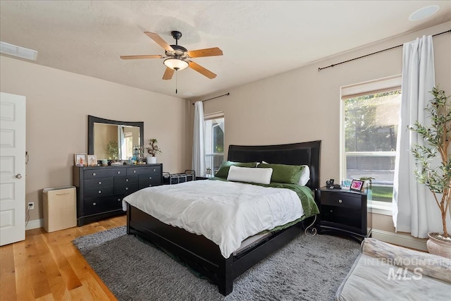 bedroom featuring a ceiling fan, baseboards, and light wood finished floors