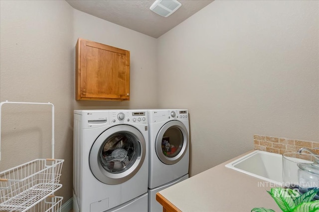 clothes washing area with visible vents, cabinet space, a sink, and washer and clothes dryer