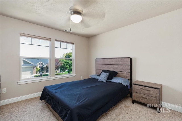 bedroom featuring a textured ceiling, carpet flooring, a ceiling fan, visible vents, and baseboards