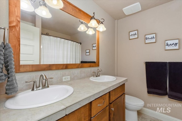 full bathroom with a sink, backsplash, toilet, and double vanity