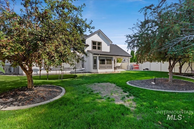 back of property featuring a yard, a trampoline, a patio area, and a fenced backyard