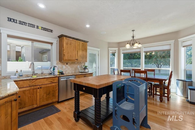 kitchen with light stone counters, brown cabinets, light wood-style flooring, decorative backsplash, and dishwasher