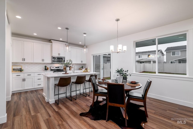 kitchen with hanging light fixtures, white cabinetry, stainless steel appliances, and light countertops