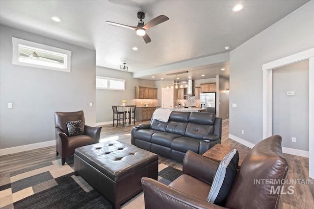 living room featuring baseboards, ceiling fan with notable chandelier, and recessed lighting