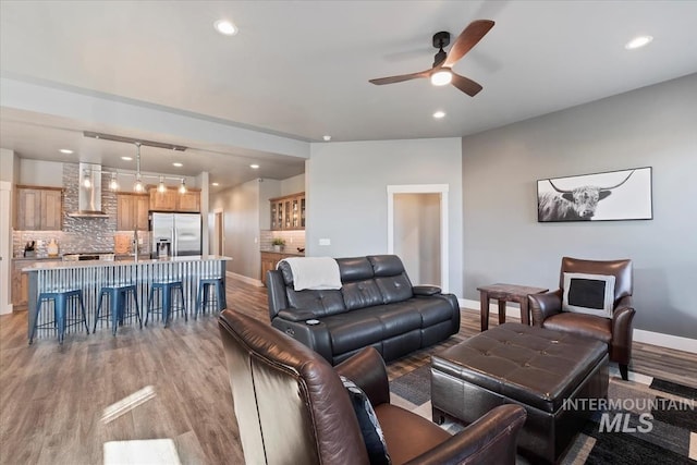 living room featuring a ceiling fan, baseboards, recessed lighting, and light wood finished floors