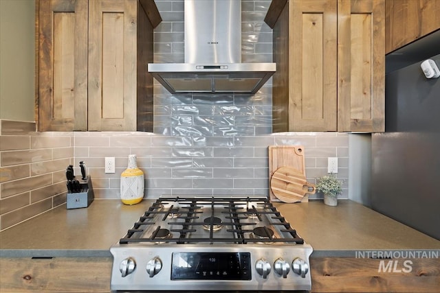 kitchen with wall chimney range hood, tasteful backsplash, and gas range