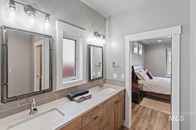 bathroom with double vanity, a sink, ensuite bath, and wood finished floors