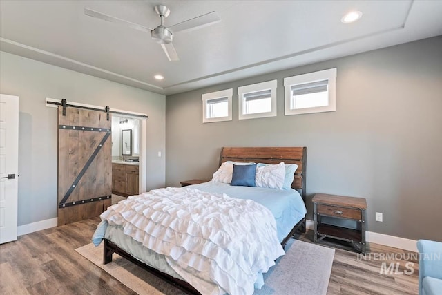 bedroom featuring baseboards, a barn door, wood finished floors, and recessed lighting