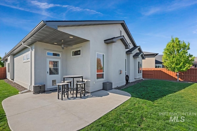 rear view of house featuring a ceiling fan, a lawn, a patio area, fence, and stucco siding