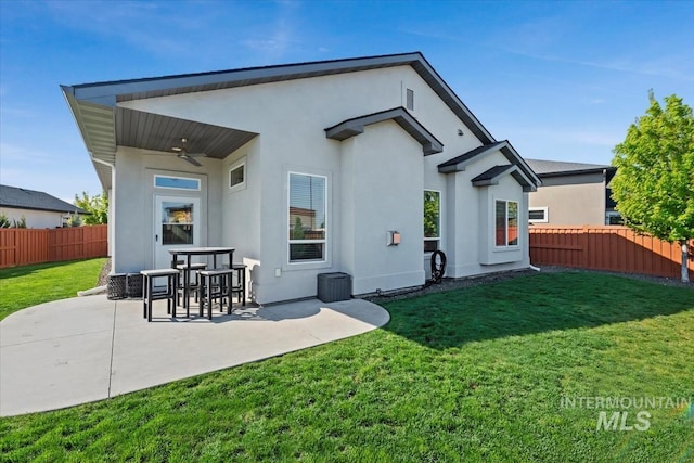 rear view of house with a fenced backyard, stucco siding, a ceiling fan, a patio area, and a yard