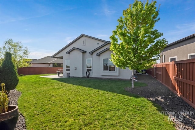 back of property with a lawn, a fenced backyard, a patio area, and stucco siding