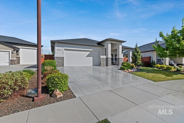 prairie-style home with a front yard, stone siding, stucco siding, an attached garage, and driveway
