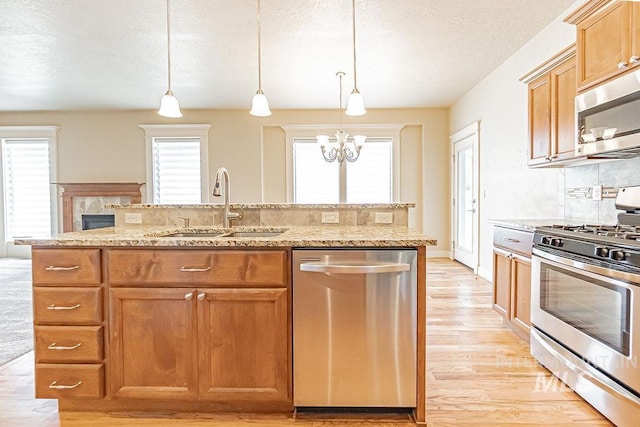 7053 W Butte Ln, Boise, ID 83704 - kitchen with appliances with stainless steel finishes, a sink, light wood-style floors, a chandelier, and a textured ceiling