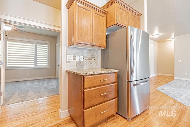 7053 W Butte Ln, Boise, ID 83704 - kitchen featuring freestanding refrigerator, light wood-type flooring, baseboards, a ceiling fan, and light stone countertops