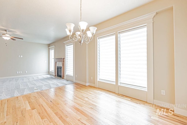 7053 W Butte Ln, Boise, ID 83704 - unfurnished living room featuring a chandelier, wood finished floors, ceiling fan, baseboards, and a tile fireplace