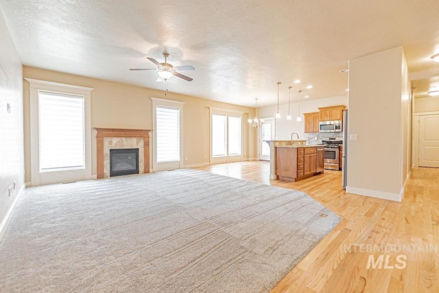 7053 W Butte Ln, Boise, ID 83704 - living room featuring a ceiling fan, baseboards, light wood-style floors, a fireplace, and a chandelier