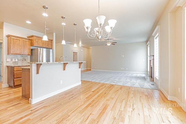 7053 W Butte Ln, Boise, ID 83704 - kitchen with freestanding refrigerator, a chandelier, a breakfast bar area, brown cabinetry, and ceiling fan