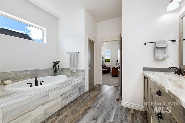 bathroom with vanity, hardwood / wood-style floors, and tiled bath