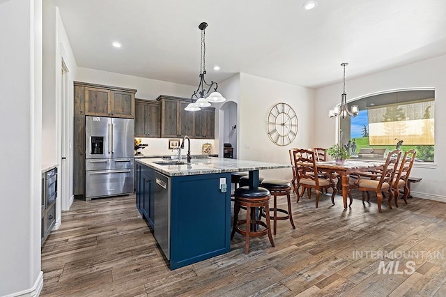 kitchen featuring an island with sink, appliances with stainless steel finishes, sink, and decorative light fixtures