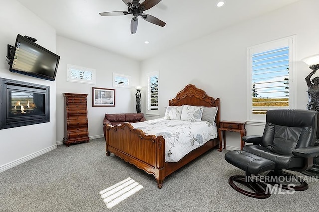 carpeted bedroom featuring ceiling fan and a multi sided fireplace