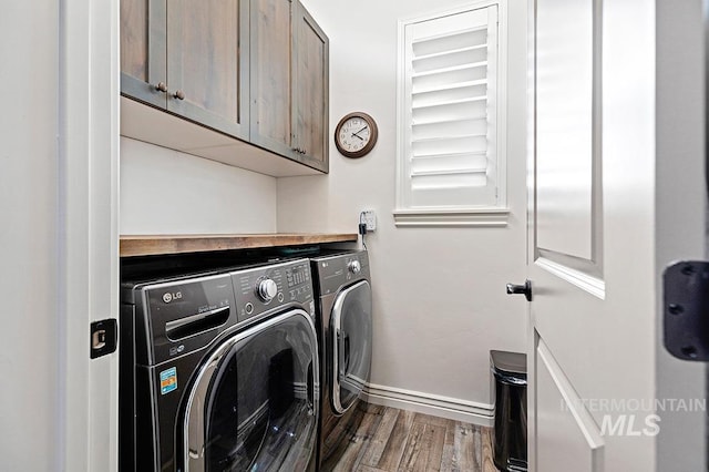 clothes washing area featuring cabinets, washer and clothes dryer, and hardwood / wood-style floors