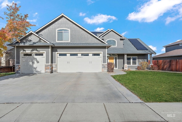 view of front of house with solar panels, a garage, and a front yard