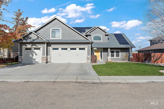 view of front facade featuring a front yard, solar panels, and a garage