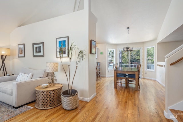 living area featuring baseboards, vaulted ceiling, and light wood-type flooring