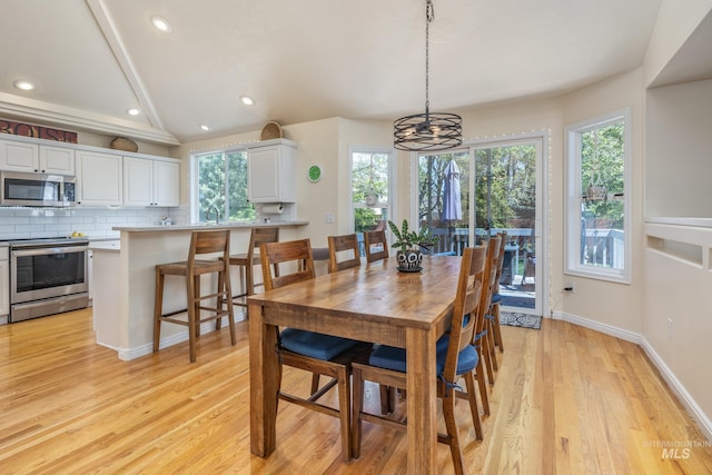 dining area with light wood-type flooring, recessed lighting, a notable chandelier, and a wealth of natural light