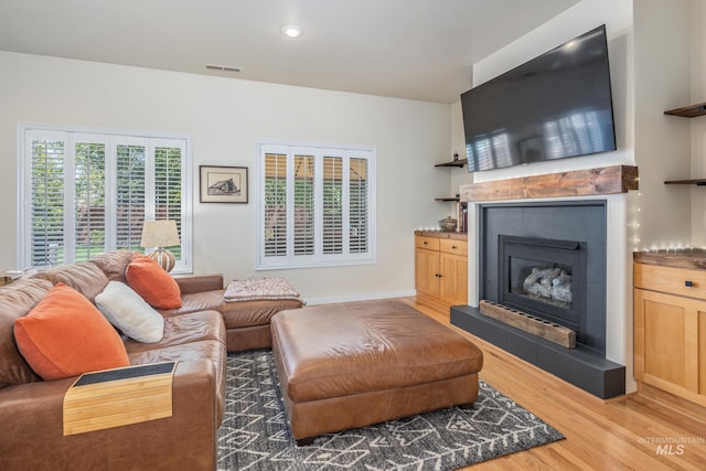 living area featuring recessed lighting, visible vents, a tiled fireplace, and light wood-style floors