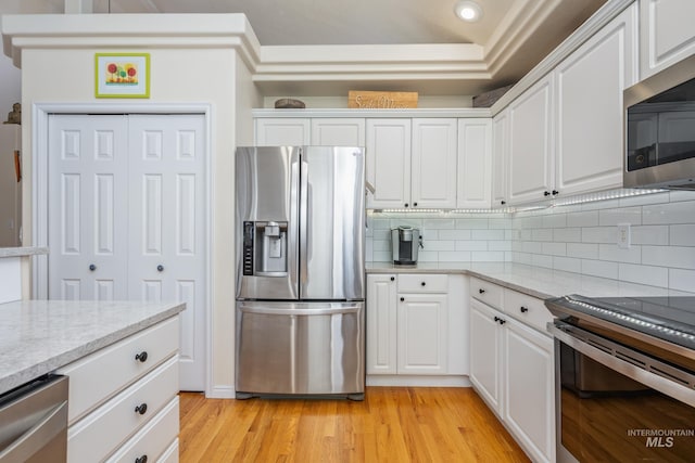 kitchen featuring white cabinets, backsplash, stainless steel appliances, and light wood-type flooring