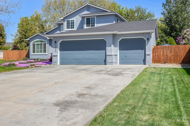 traditional-style house featuring concrete driveway, fence, a front lawn, and a garage