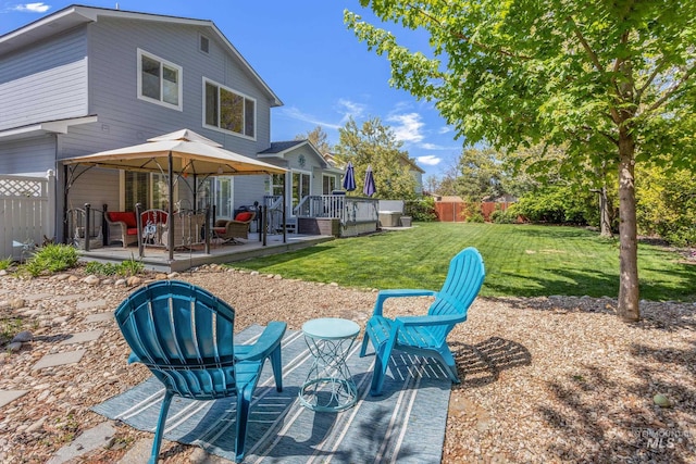 rear view of property featuring a lawn, fence, and a wooden deck