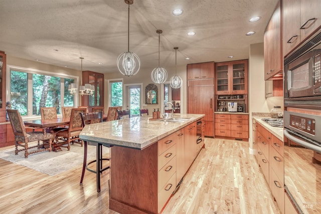 705 N Cobblestone Way, Eagle, ID 83616 - kitchen with stainless steel appliances, a sink, light wood-type flooring, a kitchen bar, and glass insert cabinets
