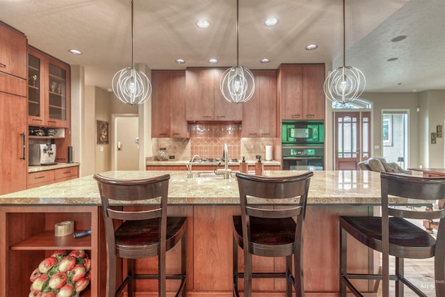 705 N Cobblestone Way, Eagle, ID 83616 - kitchen with black appliances, brown cabinetry, decorative backsplash, recessed lighting, and glass insert cabinets